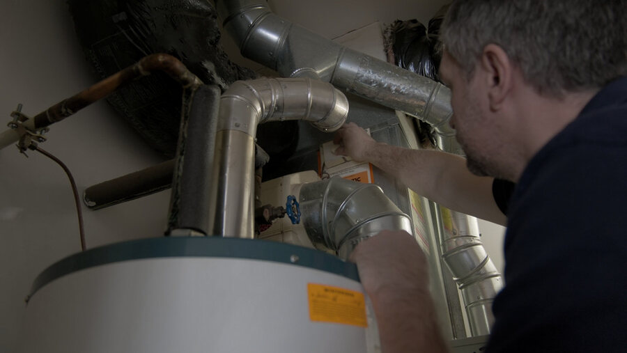 Oskar Huber servicing a water heater for Aqua Vita Plumbing